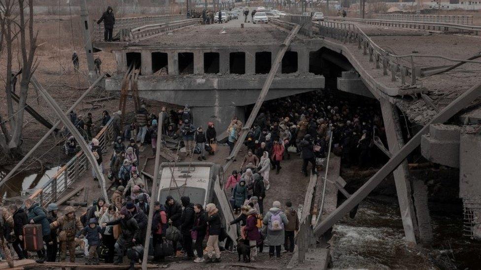 People cross a destroyed bridge as they try to leave the city of Irpin, in the Kyiv region, Ukraine 5 March 2022.