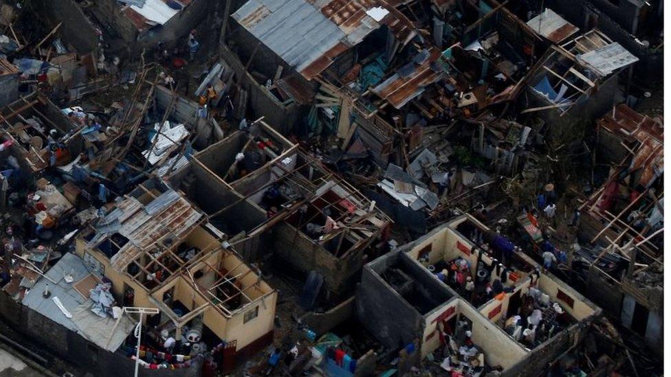 People walk next to destroyed houses after Hurricane Matthew passes Jeremie, Haiti, on 5 October 2016.