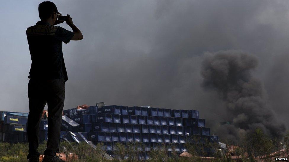 A man takes pictures at the explosion site in Binhai new district in Tianjin, China August 13, 2015.