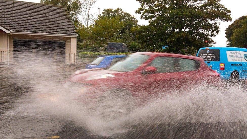 Car driving through water causing large spray