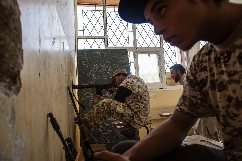 A fighter loyal to Libya's government fires his weapon from a school at Islamic State group positions in the Libyan coastal city of Sirte (29 September 2016)