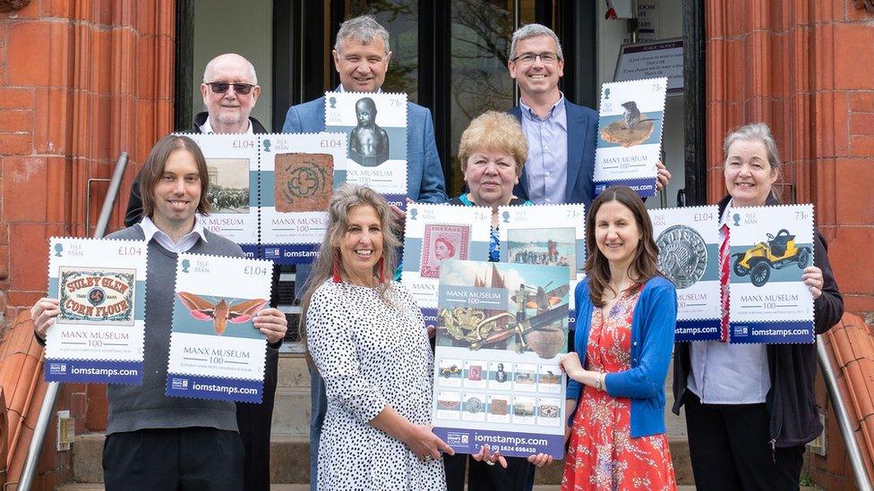 People outside the Manx Museum holding up the stamps