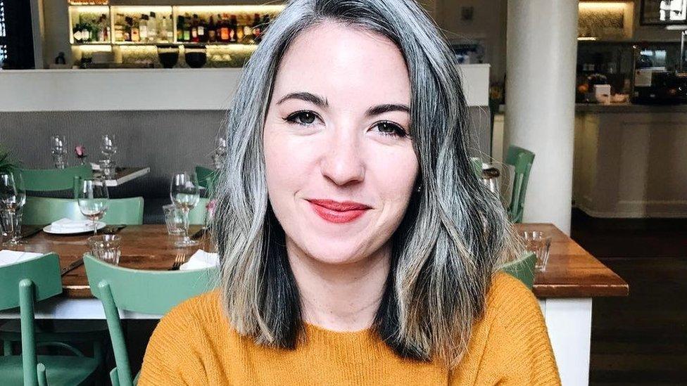 Kate, who has a grey curly bob, is pictured sitting in a restaurant