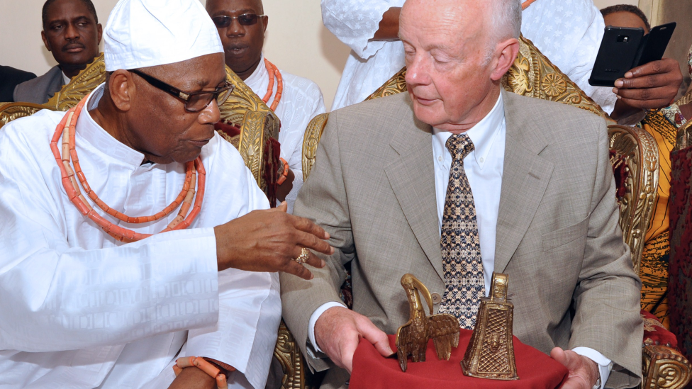 Edun Akenzua (L), a Nigerian prince, speaks with retired hospital consultant Mark Walker (R) who holds two bronze artefacts he returned to the Benin Kingdom during a ceremony in Benin City, Nigeria, on 20 June 2014