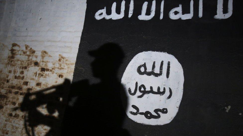 A member of the Iraqi forces walks past a mural bearing the logo of the Islamic State (IS) group in a tunnel that was reportedly used as a training centre by the jihadists, on 1 March 2017, in the village of Albu Sayf, on the southern outskirts of Mosul.