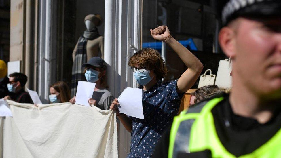 People hold up blank placards to protest against arrests of protesters in Edinburgh