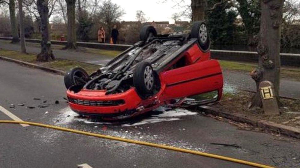 A red Vauxhall Corsa on its roof