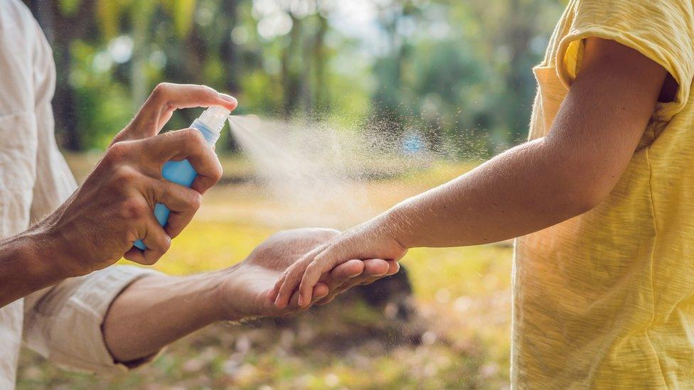 child having arm sprayed with insect repellent