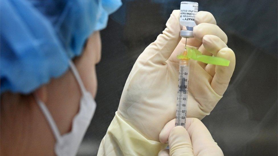 A nurse fills a syringe with the Pfizer-BioNTech vaccination