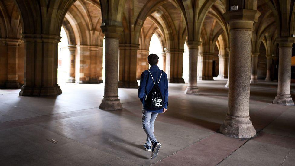 A student walks through the cloisters of Glasgow University