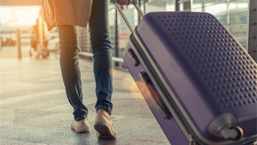 Man pulling suitcase through airport