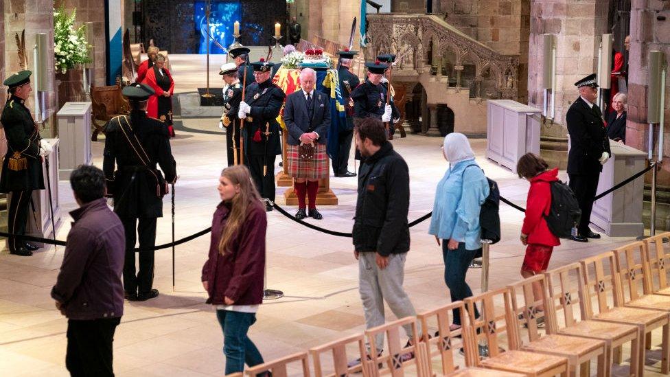 Members of the public filing past the Queen's coffin as King Charles stands vigil.