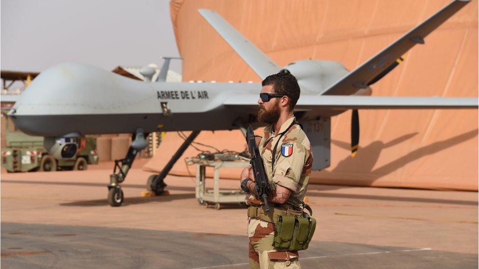 French soldier involved in the regional anti-insurgent Operation Barkhane stands guard next to a Reaper drone at the French military airbase in Niamey on March 14, 2016.