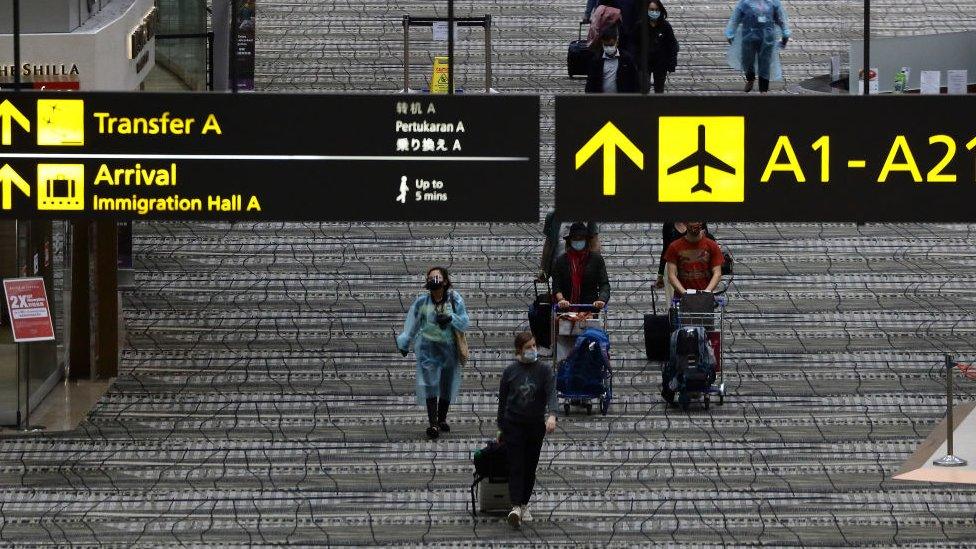 Travellers wearing protective mask walk along the transit area of Changi International Airport terminal on December 15, 2020 in Singapore.