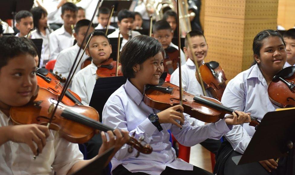 The orchestra's string section smile during a rehearsal