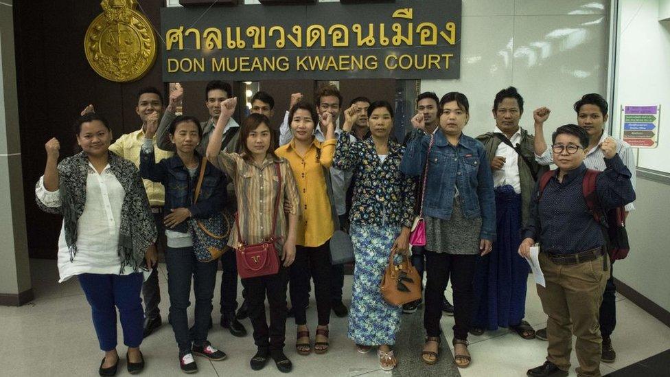 Migrant workers from Myanmar gesture defiantly for the media before entering court to face defamation charges by a Thammakaset chicken farm, after they accused the company of labour abuses, at Don Muang Magistrates Court in Bangkok on February 7, 2018.