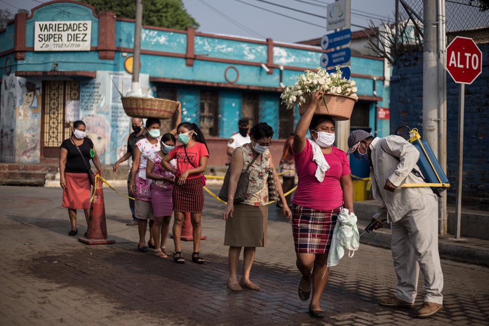 Informal vendors disinfect their bodies before entering the municipal market in Nahuizalco, Sonsonate, to sell their fruit and vegetables.