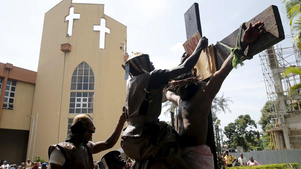 A man dressed up as a Roman soldier hangs a sign on a cross during a re-enactment of the crucifixion of Jesus Christ on Good Friday along a road near St. Leo"s Catholic church in Lagos