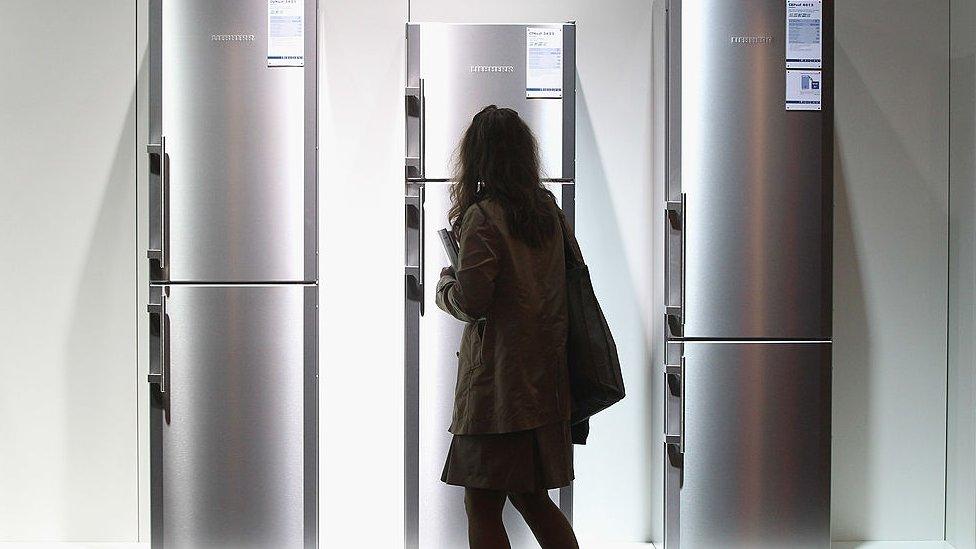 woman looks at fridges in shop