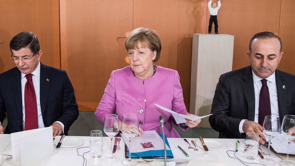 Angela Merkel sitting between the Turkish Prime Minister and Foreign Minister