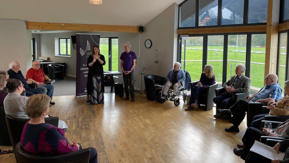 People sitting at a singing group in a hall