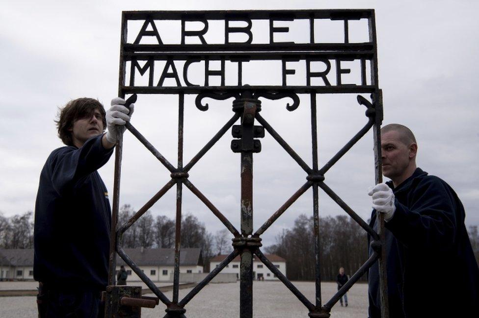 Transport company staff carry the "Arbeit macht frei" gate at the site of the former Nazi concentration camp in Dachau on 22 February, 2017.