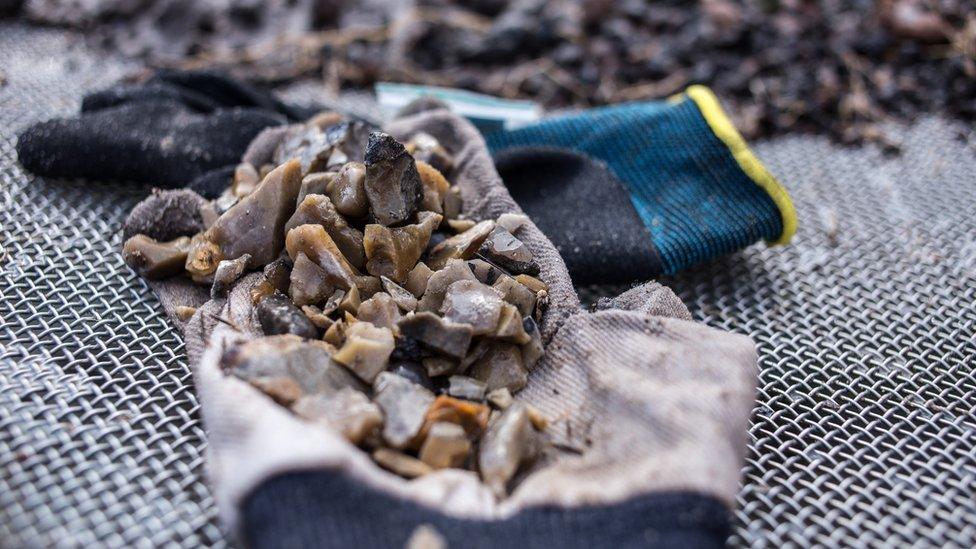 A pile of stone-like objects sit on top of an empty glove