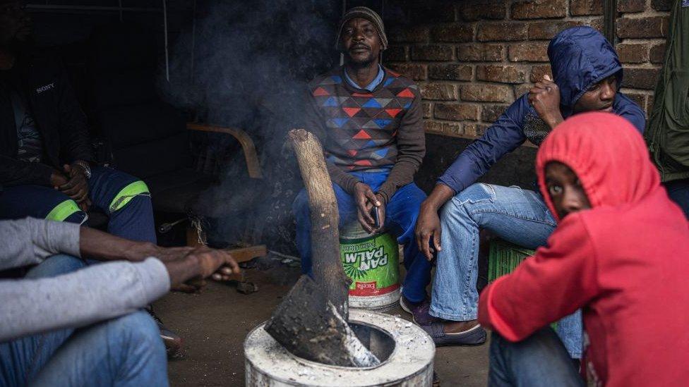 People warming themselves by a fire outside a hijacked building in Johannesburg, South Africa