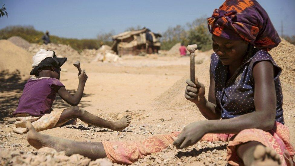 Woman and child breaking rocks from cobalt mine