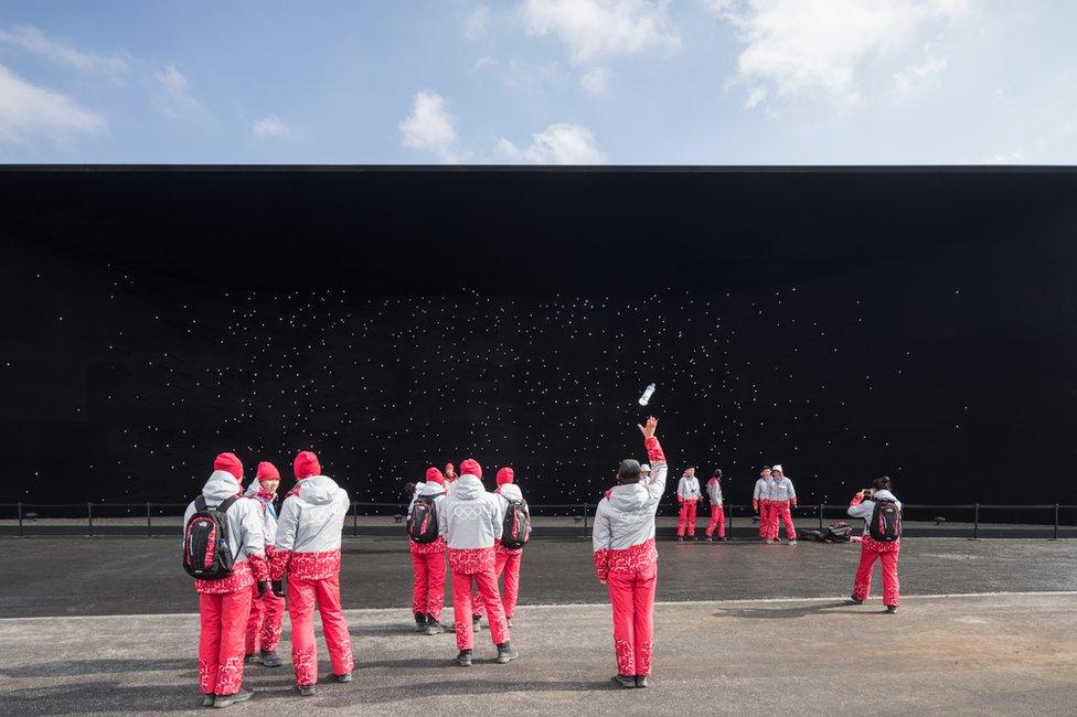 A group of tourists standing in front of a black wall