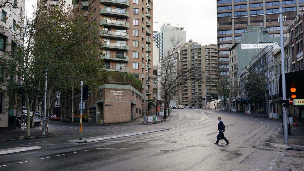 A man crosses a deserted street in central Sydney during lockdown