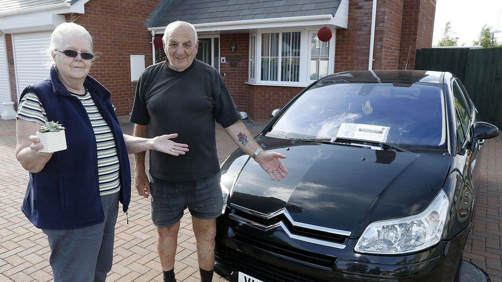 Tom and Julia Ebenezer in front of the parked car