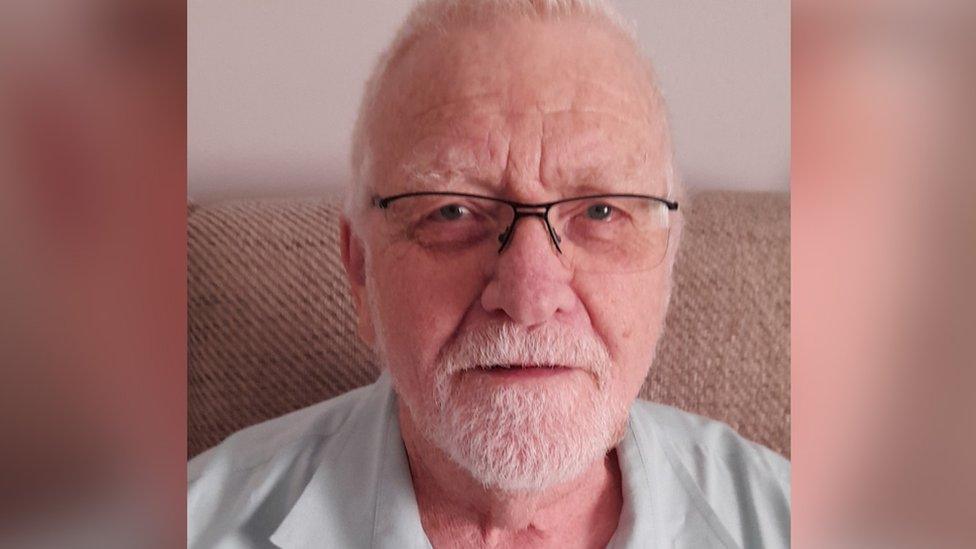 Tony Leach sitting on his sofa. He has grey hair and glasses