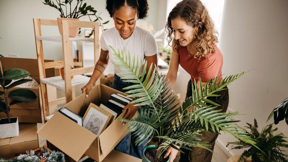 Two young women unpacking boxes in a flat