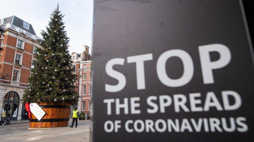 A Christmas tree is seen alongside coronavirus signage in Covent Garden, London