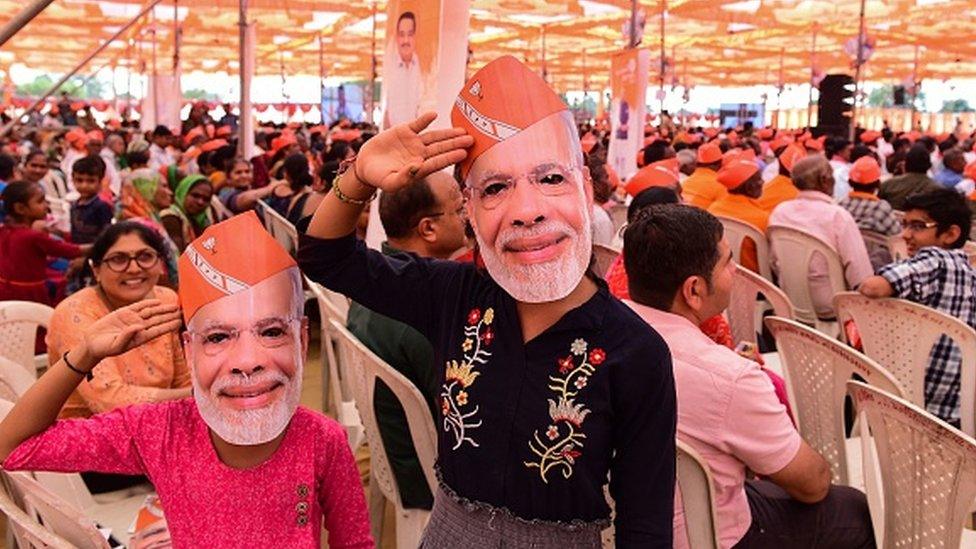 BJP supporters cheer wearing Modi masks during an election rally