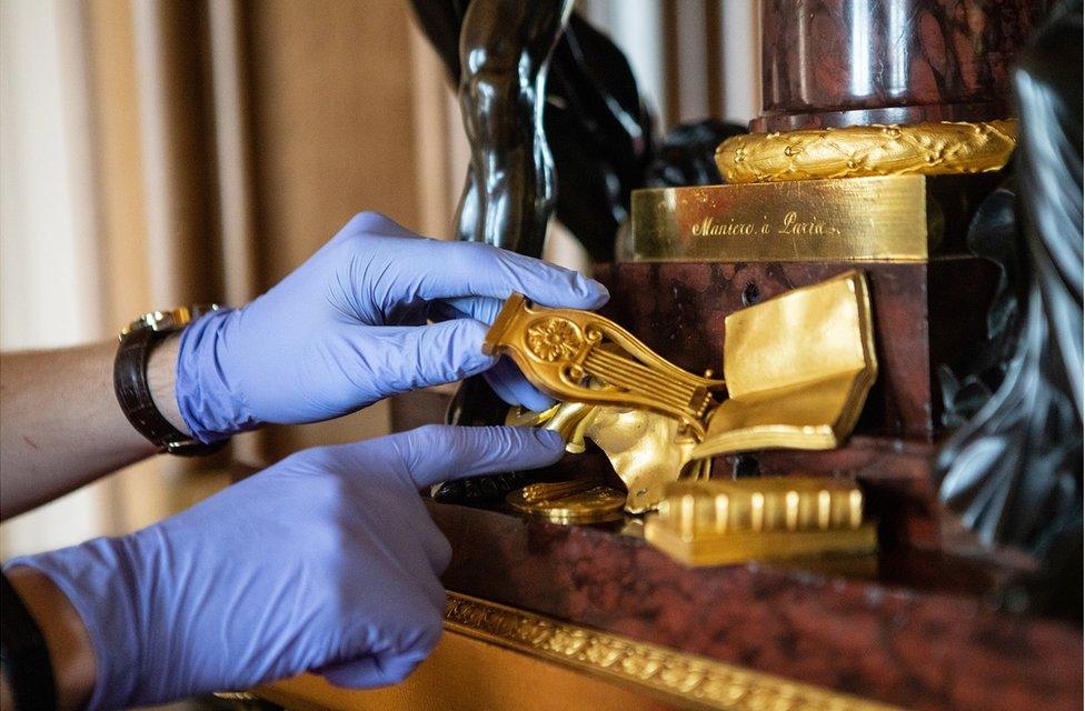 Fjodor points out the keyhole at the base of a large clock