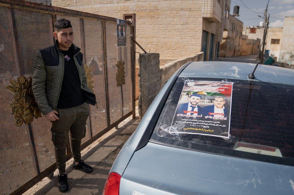 Abdel Wadi stands next to a poster of his relatives Ibrahim and Ahmed Wadi, who were killed last week