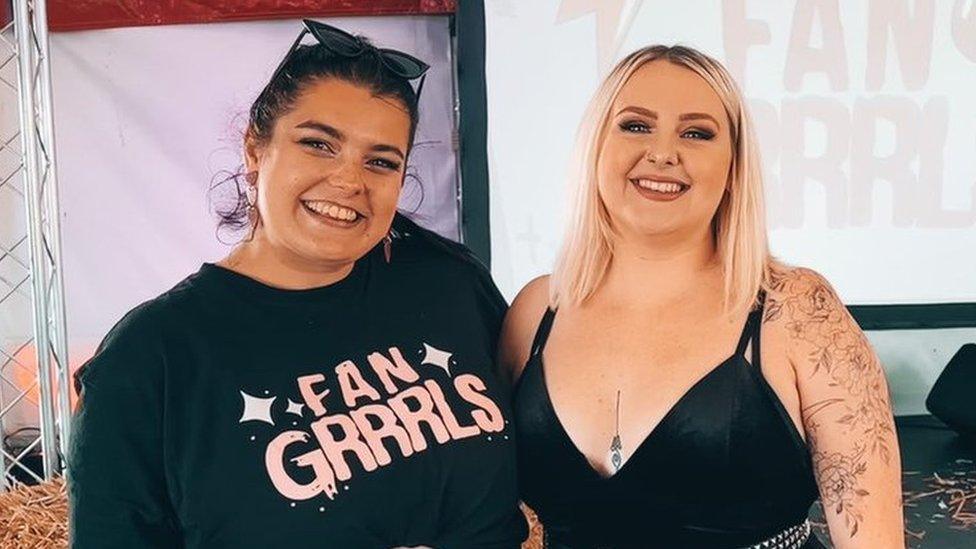 Jess Dyer (L) and Dan Hewitt (R) standing in front of a projector that says Fan Grrrls on it