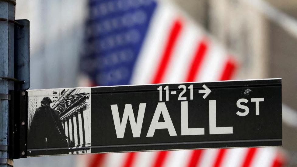 A stock image shows a close up of a road sign on Wall Street in New York