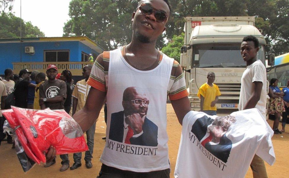 A man wearing a George Weah t-shirt attempts to sell his wares in Liberia