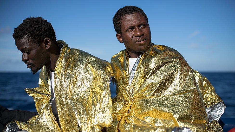 West African men relax on the deck of the Topaz Responder, MOAS", Migrant Offshore Aid Station search and rescue vessel as it makes its way to Vibo Valentia, in Italy November 23, 2016 in Pozzollo Italy.