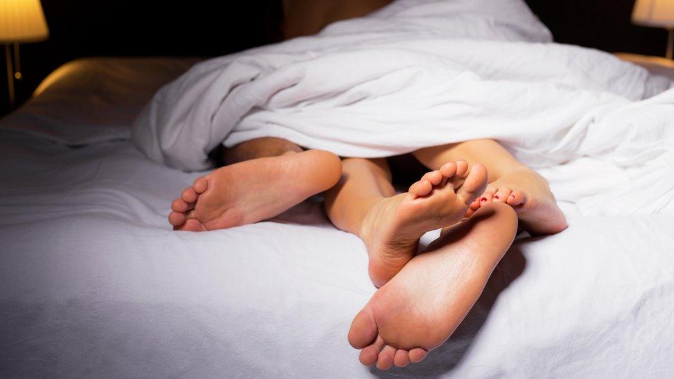 Couple's feet sticking out of the end of a bed