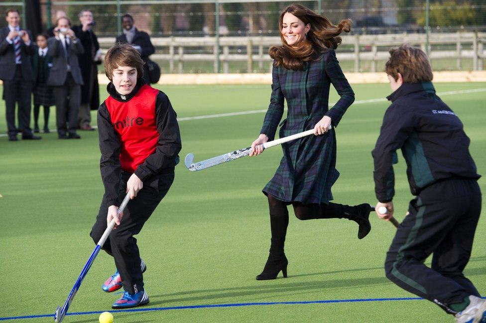 Catherine, Duchess of Cambridge plays field hockey in a coat and heels at St Andrew's School on November 30, 2012