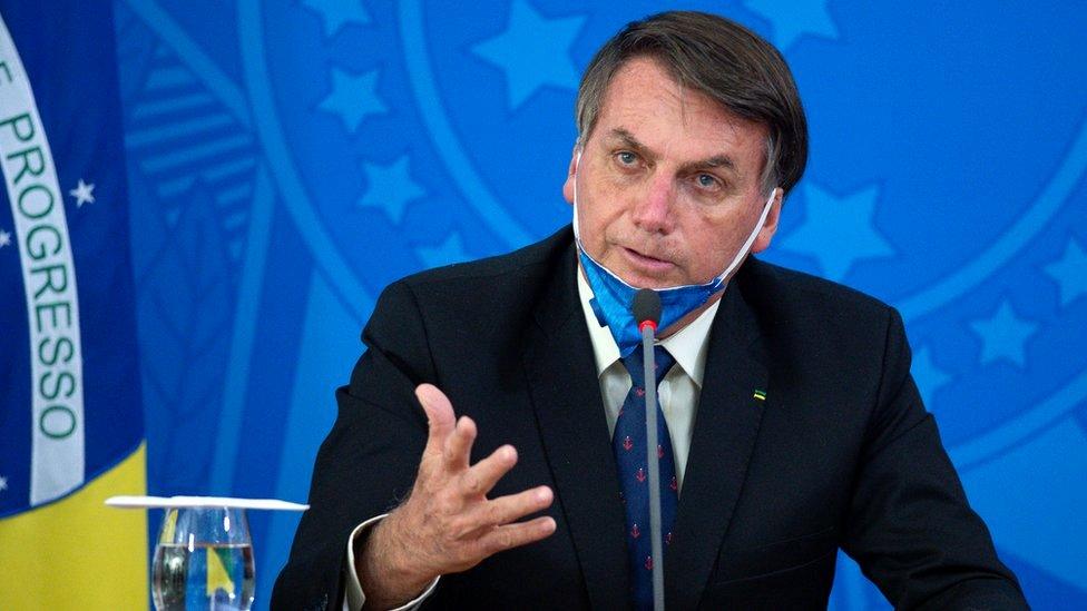 Jair Bolsonaro, President of Brazil, takes off his protective mask to speak to journalists during a press conference about outbreak of the coronavirus in Brasilia, Brazil, 20 March 2020