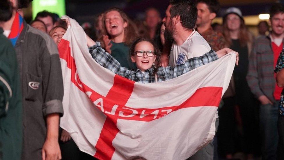 Young England fan celebrates with large England flag.