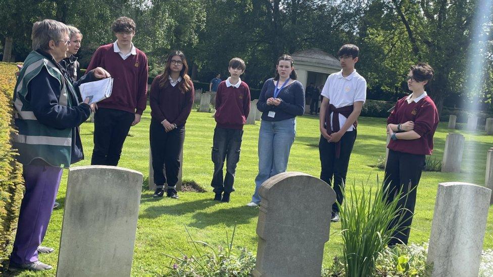 Group of six children standing beside war graves