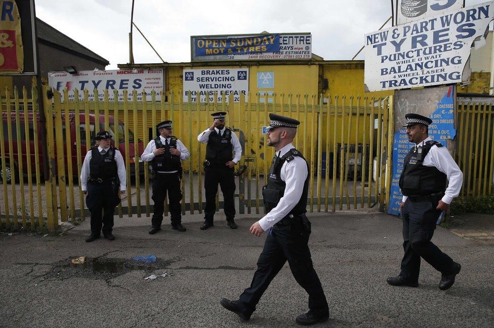 Police officers stand on duty in Barking, east London on following a dawn raid on a property,