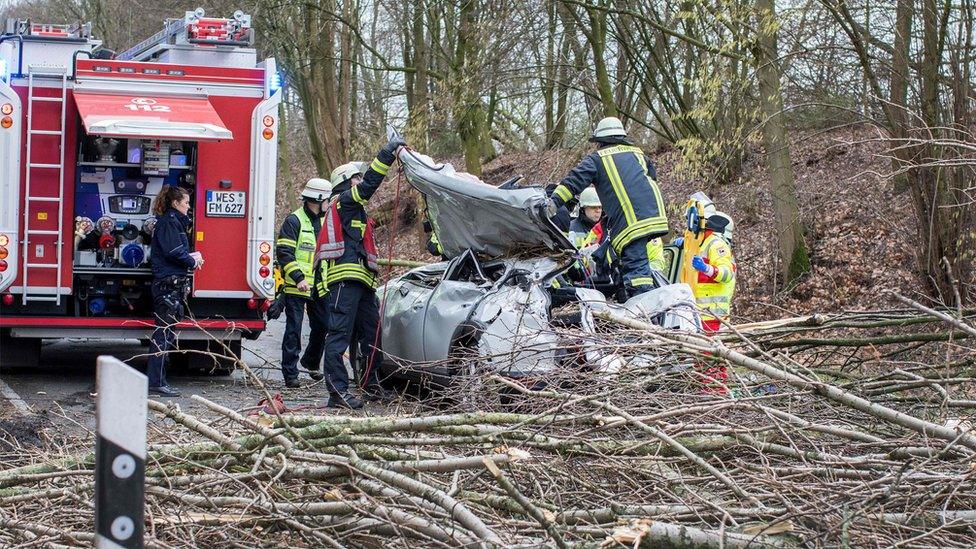 firefighters surround and work on a crushed car