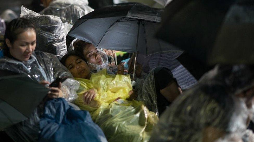 People take cover from torrential rain as they prepare for funeral ceremonies in Bangkok. Photo: 24 October 2017